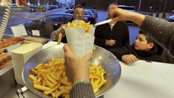 A woman serves Belgian fries to customers at a chips stand, in Brussels.